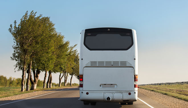 White intercity bus is driving along the road.